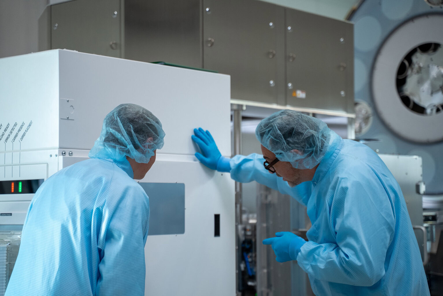 Engineers inspecting glass wafers inside RECIF's SMART EFEM, interfaced with HELIOS